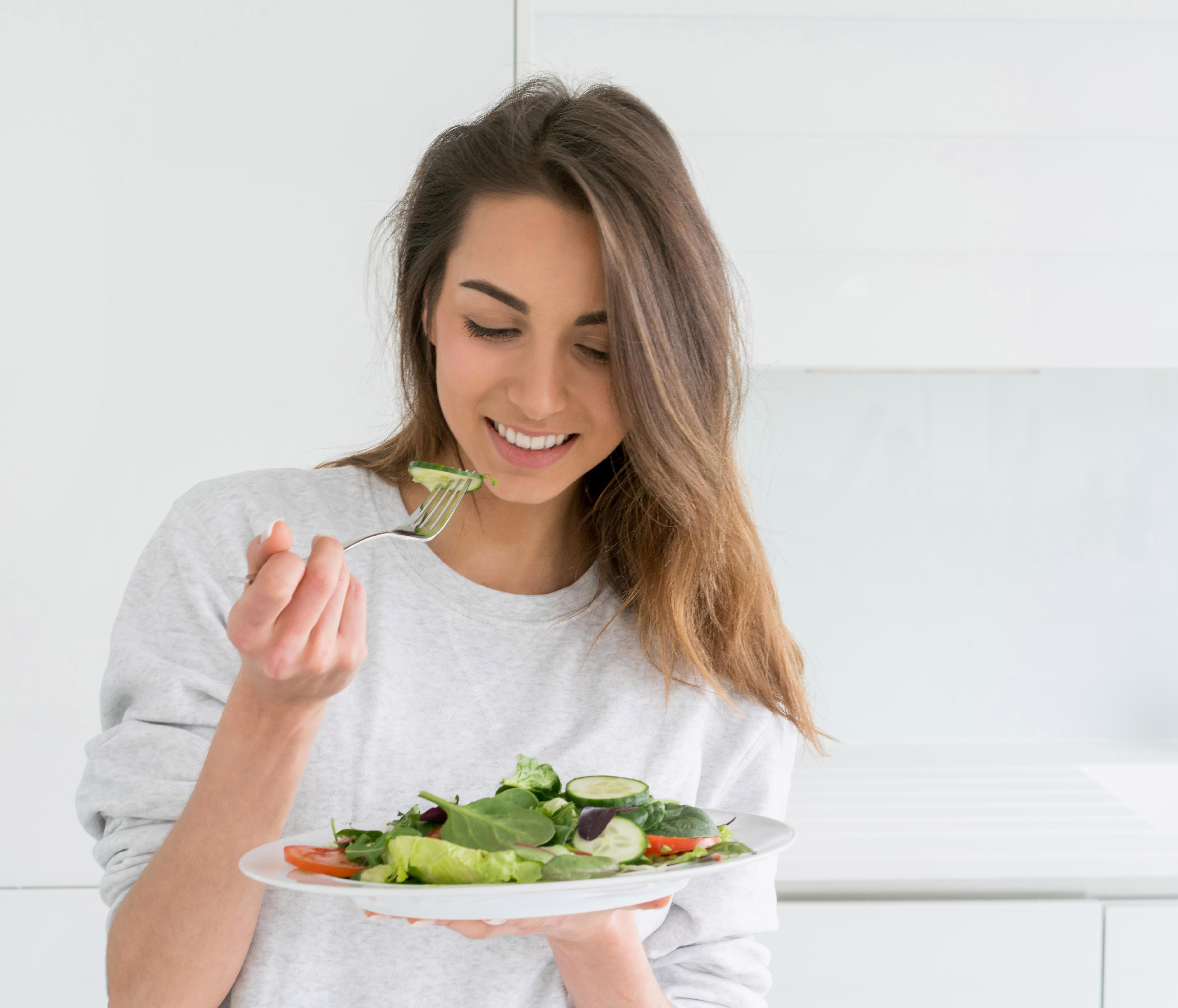 Девушка делает удовольствие. Девушка ест салат. Девушка с салатом. Здоровое питание девушка.